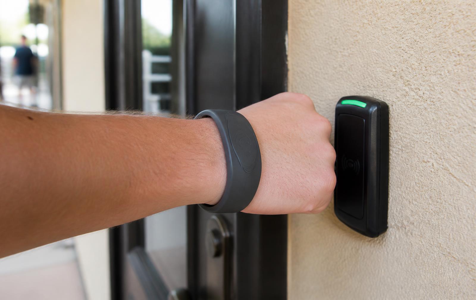 Un ospite avvicina il braccialetto RFID al lettore accanto a una porta